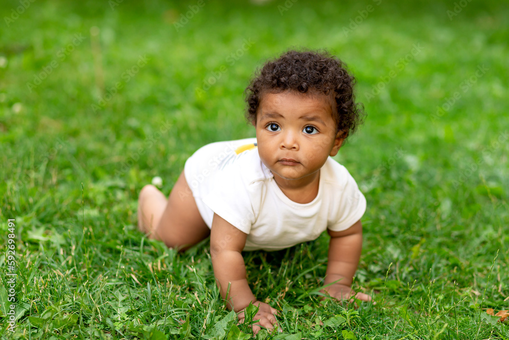 happy african-american baby boy on the green grass lawn in summer crawling happy african-american baby boy on the green grass lawn in summer crawling