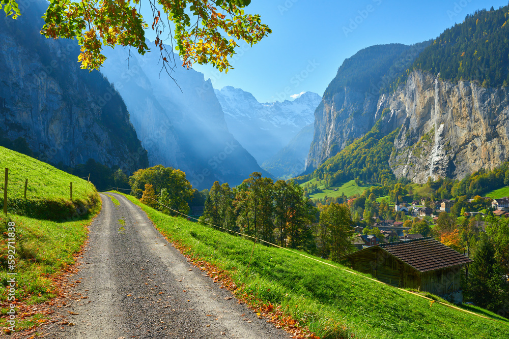 Morning mountain view with old wooden barn and road among the meadow in Lauterbrunnen valley in Switzerland.