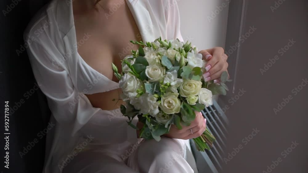Female in dress hold in hands bouquet with ribbons of white rose flowers. Gift for a woman, holiday, wedding bouquet of the bride. Floristics. Female in dress hold in hands bouquet with ribbons of white rose flowers. Gift for a woman, holiday, wedding bouquet of the bride. Floristics.
