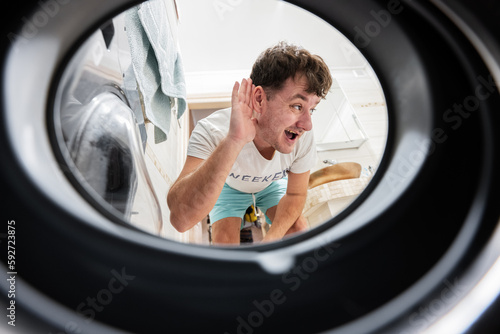 Man view from washing machine inside. Male does laundry daily routine. Listens to the sound inside.