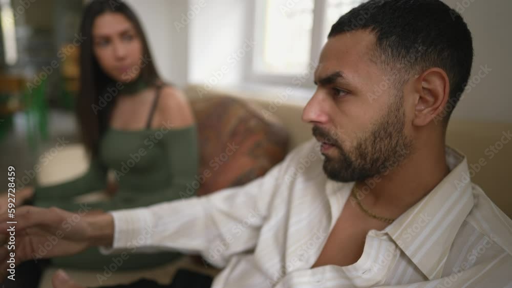 Angry muted boyfriend sitting in silence during argument with girlfriend. Upset young man with serious expression feeling annoyed by girlfriend's nagging Angry muted boyfriend sitting in silence during argument with girlfriend. Upset young man with serious expression feeling annoyed by girlfriend's nagging