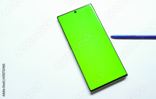 Smartphone mockup with green screen, stylus pen on the side, top view, isolated on white background