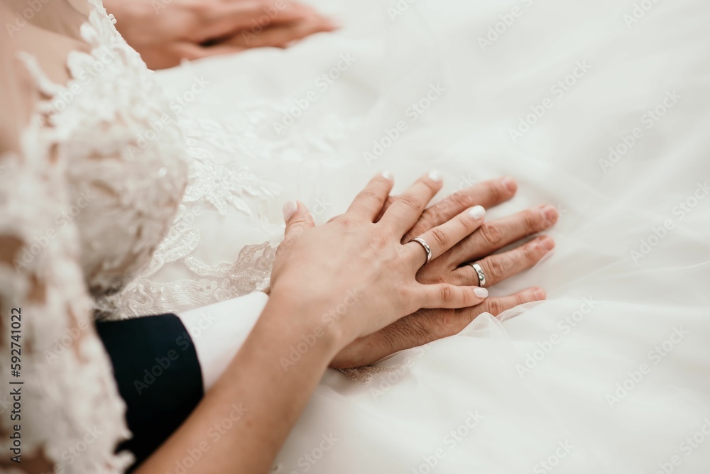 Hands of the groom and bridge with rings on the white wedding dress Hands of the groom and bridge with rings on the white wedding dress