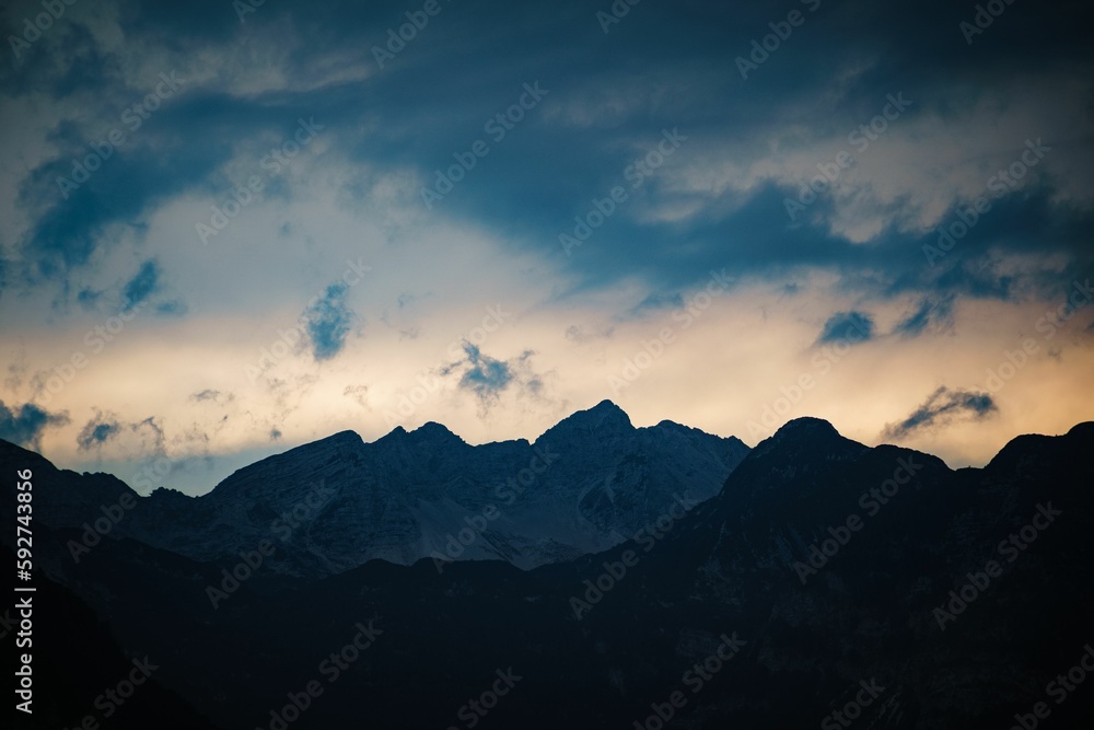 Landscape of mountains range with clouds at sunset wth dark clouds