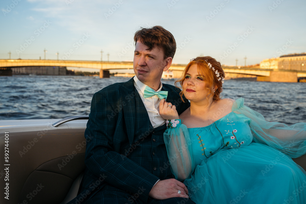 Young newlyweds couple in motor boat in sunset.