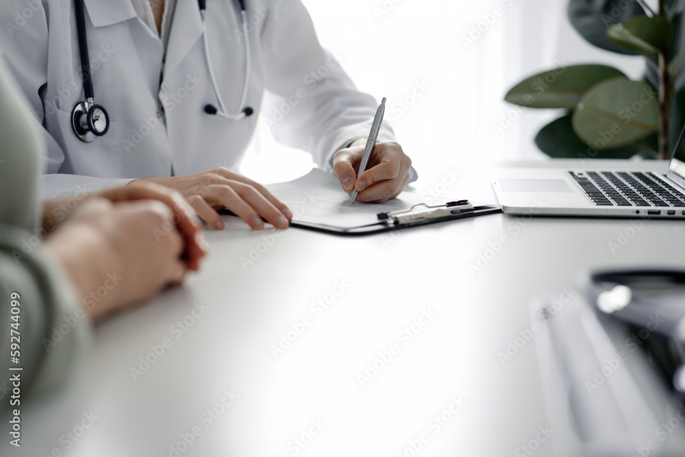 Doctor and patient discussing current health examination while sitting at the desk in clinic office, closeup. Medicine concept Doctor and patient discussing current health examination while sitting at the desk in clinic office, closeup. Medicine concept