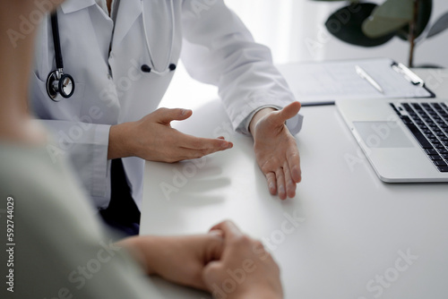 Doctor and patient discussing current health examination while sitting at the desk in clinic office, closeup. Perfect medical service and medicine concept