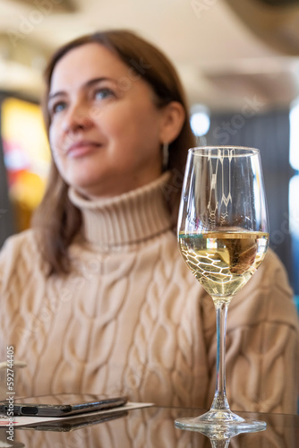 glass of wine in a restaurant or cafe and a girl out of focus. vertical