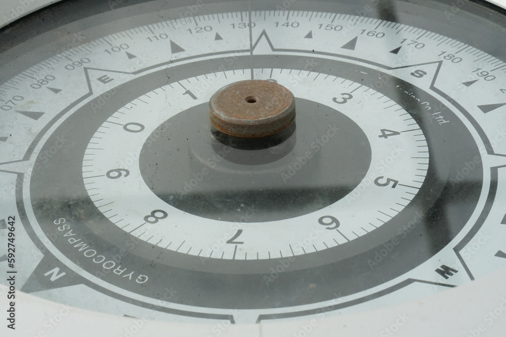 A gyrocompass card or compass rose of repeater in detail view installed on the bridge of cargo vessel. Gyrocompass is a type of non-magnetic compass use for navigation of the ships during movement. A gyrocompass card or compass rose of repeater in detail view installed on the bridge of cargo vessel. Gyrocompass is a type of non-magnetic compass use for navigation of the ships during movement.