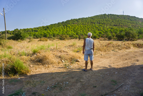 Old farmer man looking distant on wasteland.