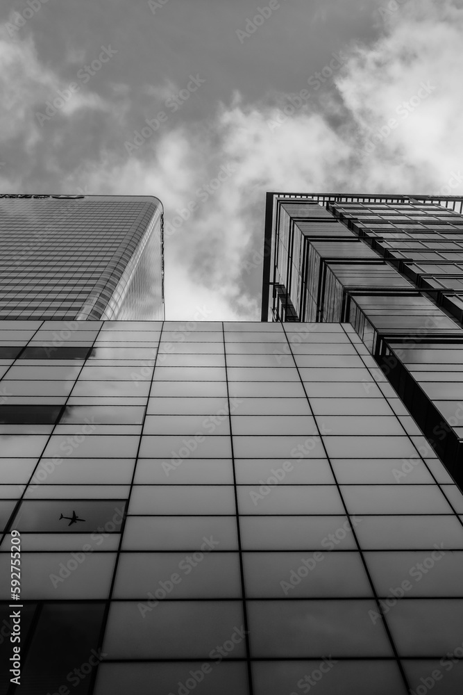 Fototapeta premium czarno białe, w oknach wieżowca odbijający się lecący samolot