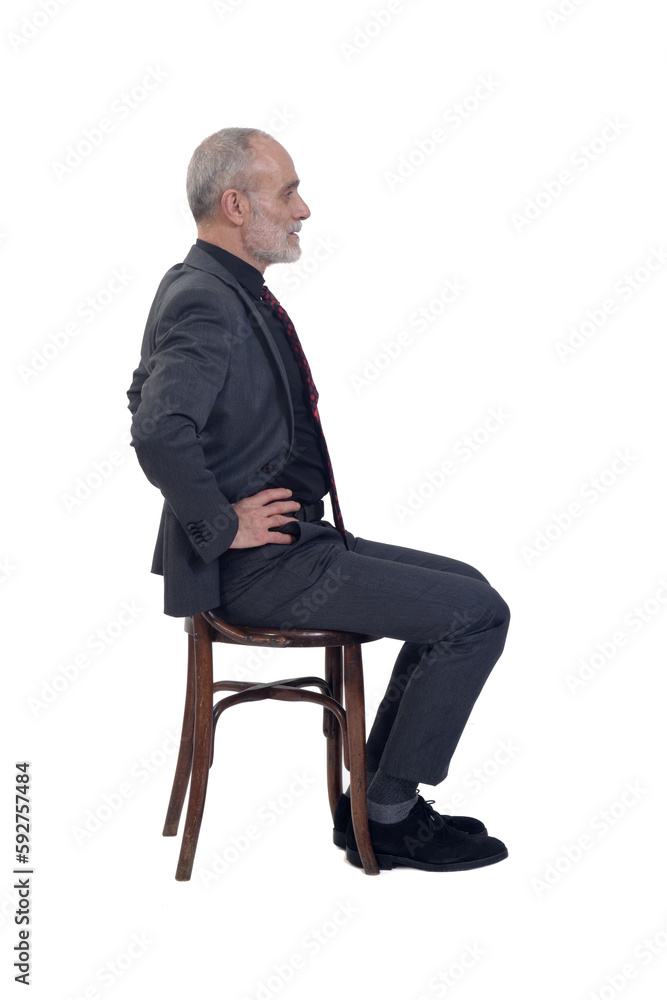side view of a man sitting on chair with suit and tie and arms akimbo on white background side view of a man sitting on chair with suit and tie and arms akimbo on white background