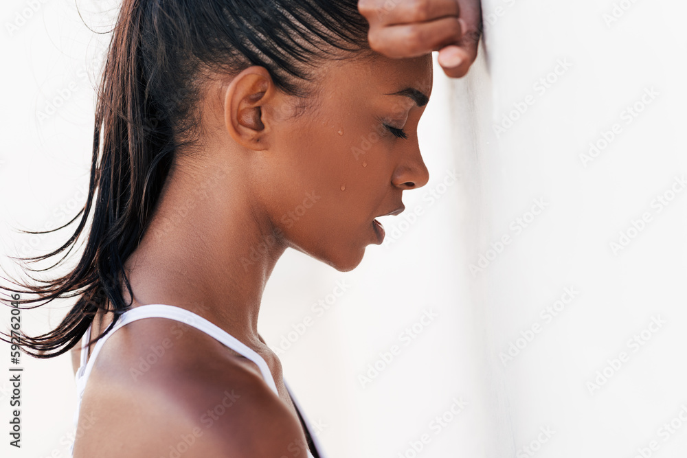 Tired and sweating woman relaxing at white wall. Close-up of a female with closed eyes leaning on her hand taking a break during a workout. Tired and sweating woman relaxing at white wall. Close-up of a female with closed eyes leaning on her hand taking a break during a workout.