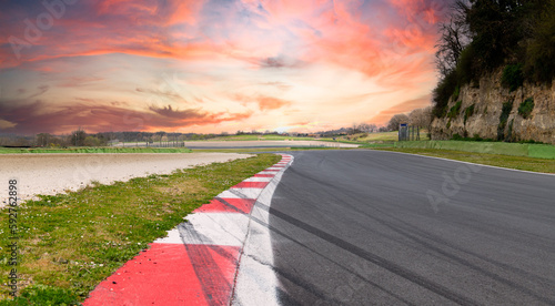 Motor sport asphalt race track and curbs with skid marks, low angle view and sunset sky light