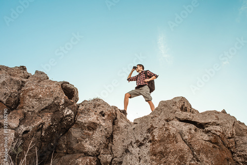 Young man hiker getting ready to climb up mountain going on an adventure looking up at the challenge before him. Believe in yourself  overcoming challenges  pushing forward concept. 