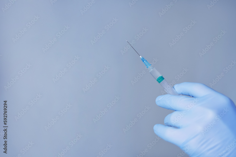 Hand in blue gloves holding syringe Hand in blue gloves holding syringe