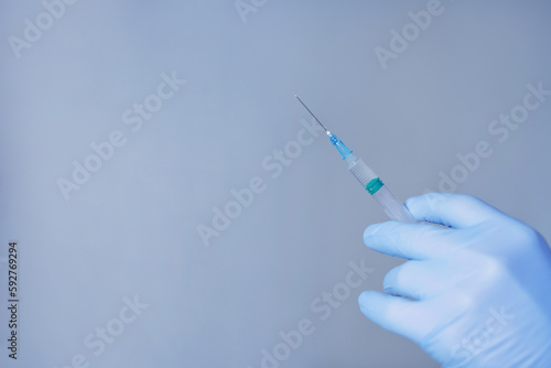 Hand in blue gloves holding syringe