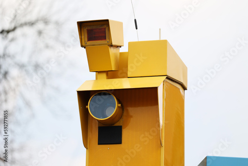 Żółty fotoradar robi zdjęcia wykroczeń drogowych kierowcom samochodów. 