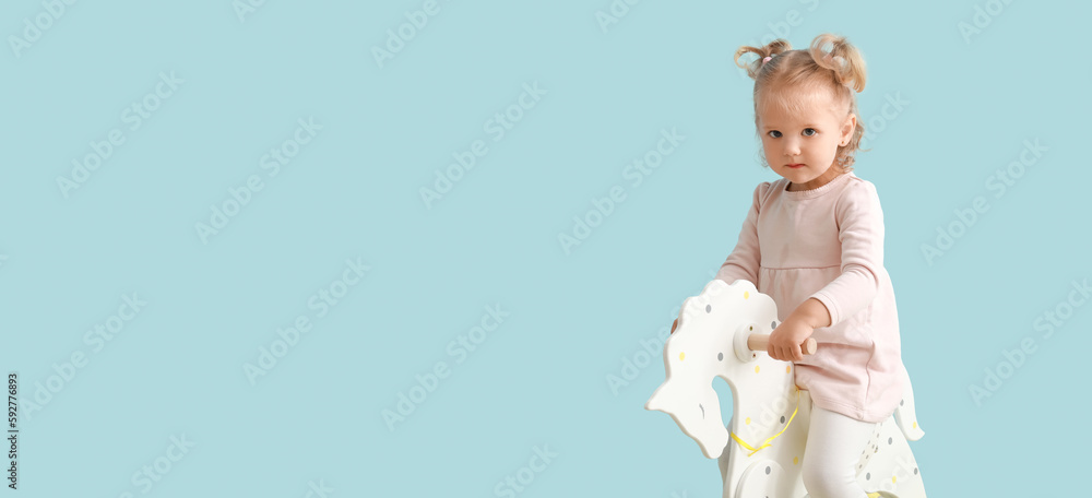 Adorable baby girl with rocking horse on light blue background with space for text - obrazy, fototapety, plakaty 