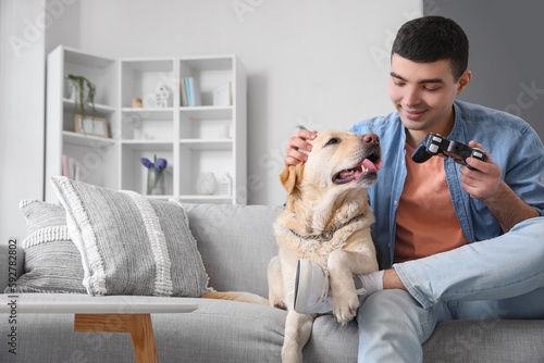 Young man with cute Labrador dog playing video game at home © Pixel-Shot