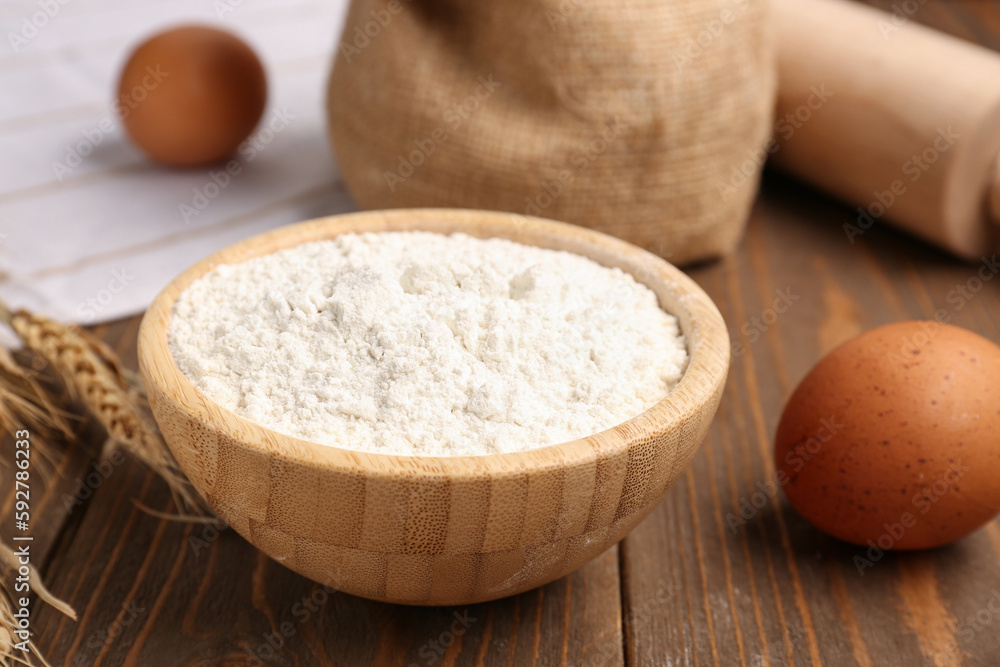 Bowl with wheat flour on wooden table, closeup Bowl with wheat flour on wooden table, closeup