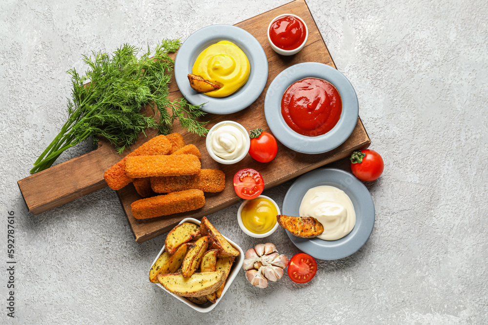 Composition with different sauces, snacks and vegetables on grey grunge table Composition with different sauces, snacks and vegetables on grey grunge table