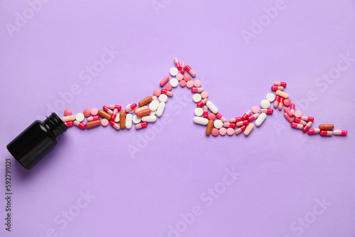 Bottle and cardiogram made of pills on lilac background