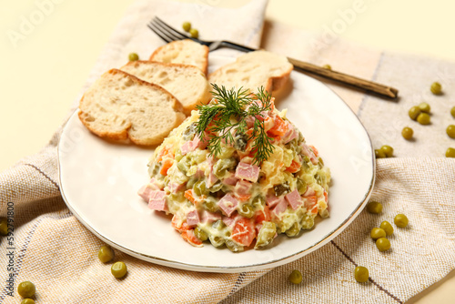 Plate of tasty Olivier salad on yellow background
