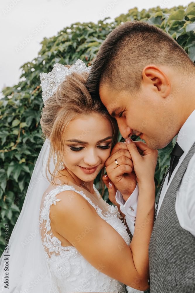 Fototapeta premium bride and groom in the garden among greenery. Royal wedding concept. Gorgeous dress of the bride. Tenderness and calmness. Portrait photography