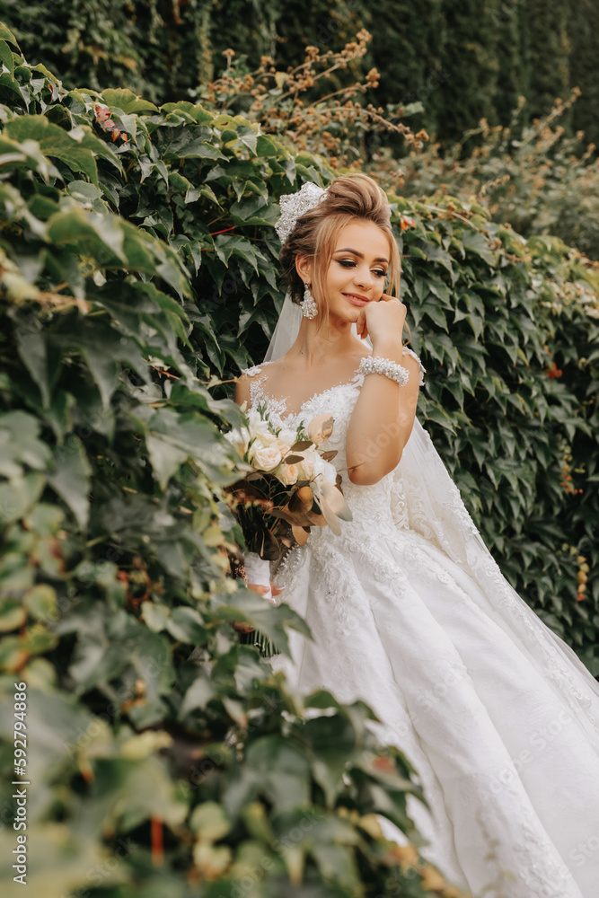 bride in the garden among greenery. Royal wedding concept. Chic bride's dress with a long train. Tenderness and calmness. Portrait photography