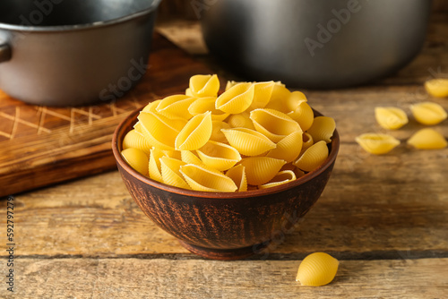 Bowl with raw conchiglie pasta on wooden background photo