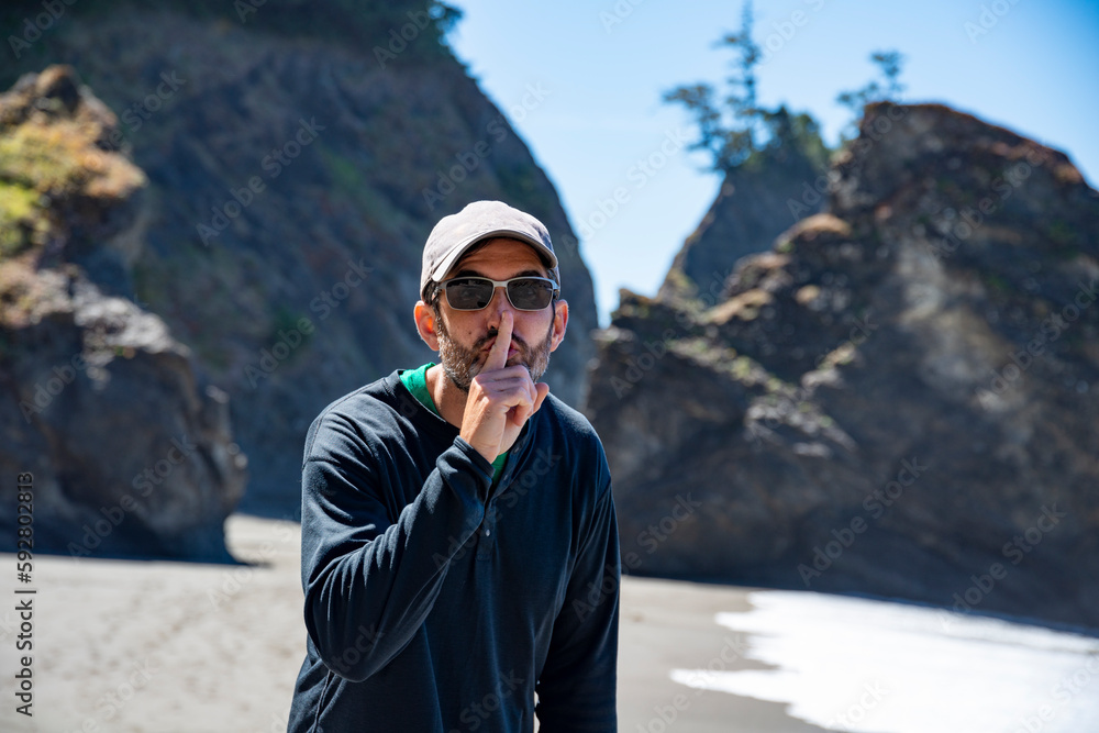 Adventurous athletic man motioning to be quiet on a beach on the rugged coastline of the Pacific Northwest.
Adventurous athletic man motioning to be quiet on a beach on the rugged coastline of the Pacific Northwest.