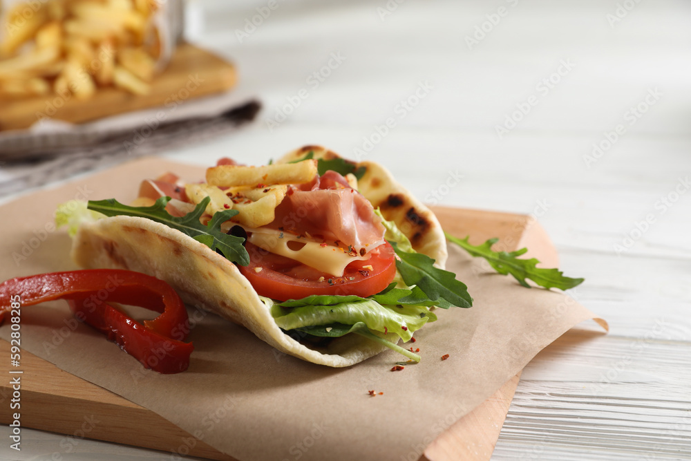 Delicious pita wrap with jamon, vegetables and greens on wooden table Delicious pita wrap with jamon, vegetables and greens on wooden table