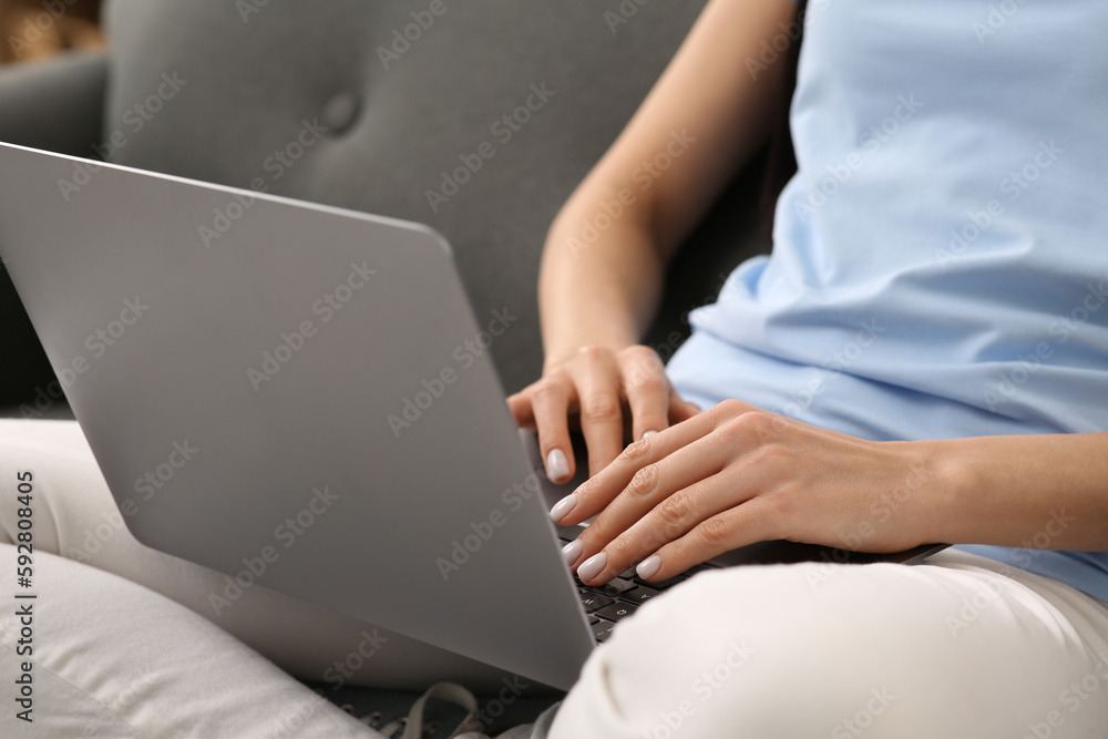 Naklejka premium Woman working with laptop on sofa, closeup