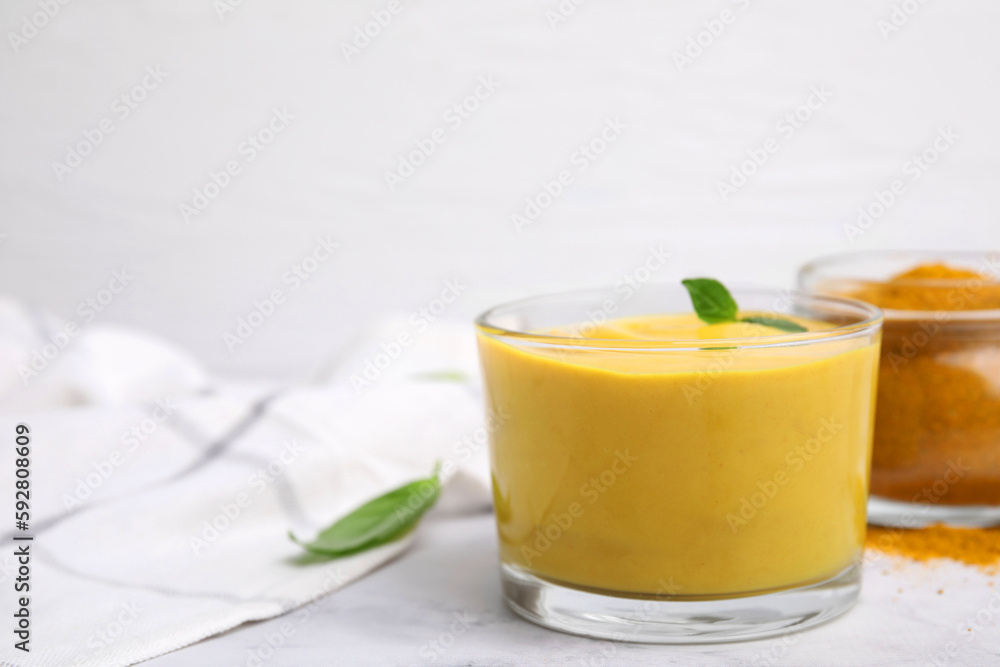 Tasty curry sauce, powder and basil leaves on white table, closeup. Space for text Tasty curry sauce, powder and basil leaves on white table, closeup. Space for text