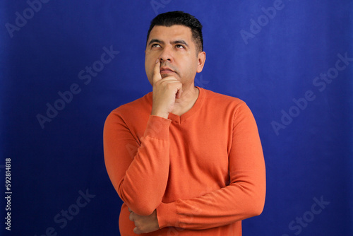Adult dark-skinned Latino man in his forties appears pensive and thoughtful 