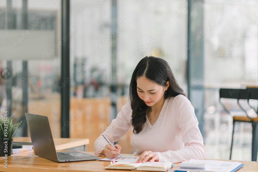 A portrait of a smiling, young, beautiful, professional, and confident millennial Asian businesswoman using a digital tablet to analyze sales data at a co-working space. A portrait of a smiling, young, beautiful, professional, and confident millennial Asian businesswoman using a digital tablet to analyze sales data at a co-working space.
