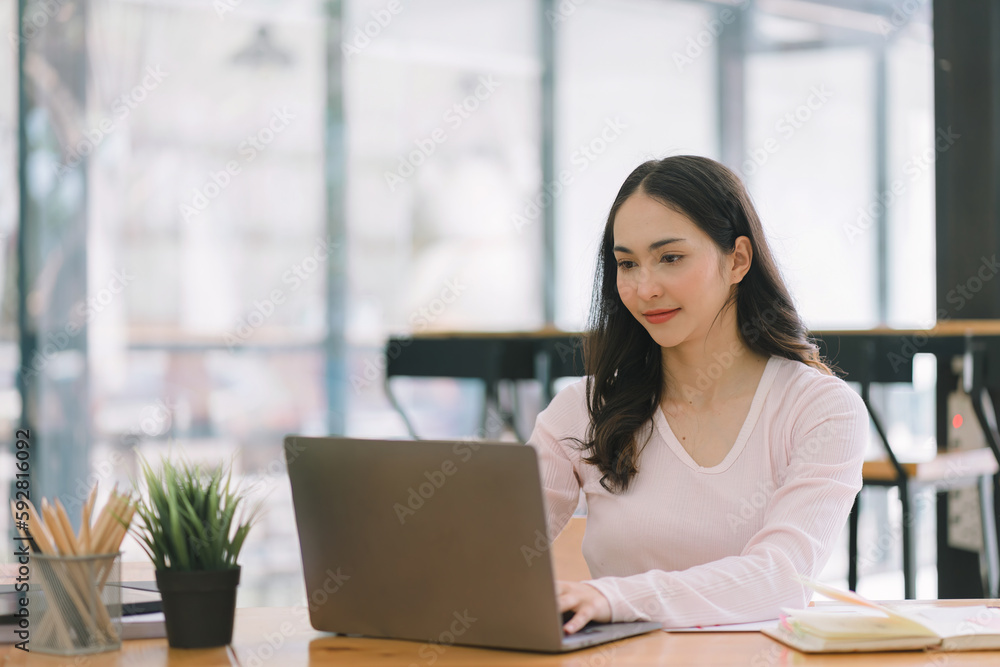 A portrait of a smiling, young, beautiful, professional, and confident millennial Asian businesswoman using a digital tablet to analyze sales data at a co-working space. A portrait of a smiling, young, beautiful, professional, and confident millennial Asian businesswoman using a digital tablet to analyze sales data at a co-working space.