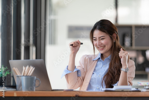 Asian women celebrate success or happy poses with a laptop.