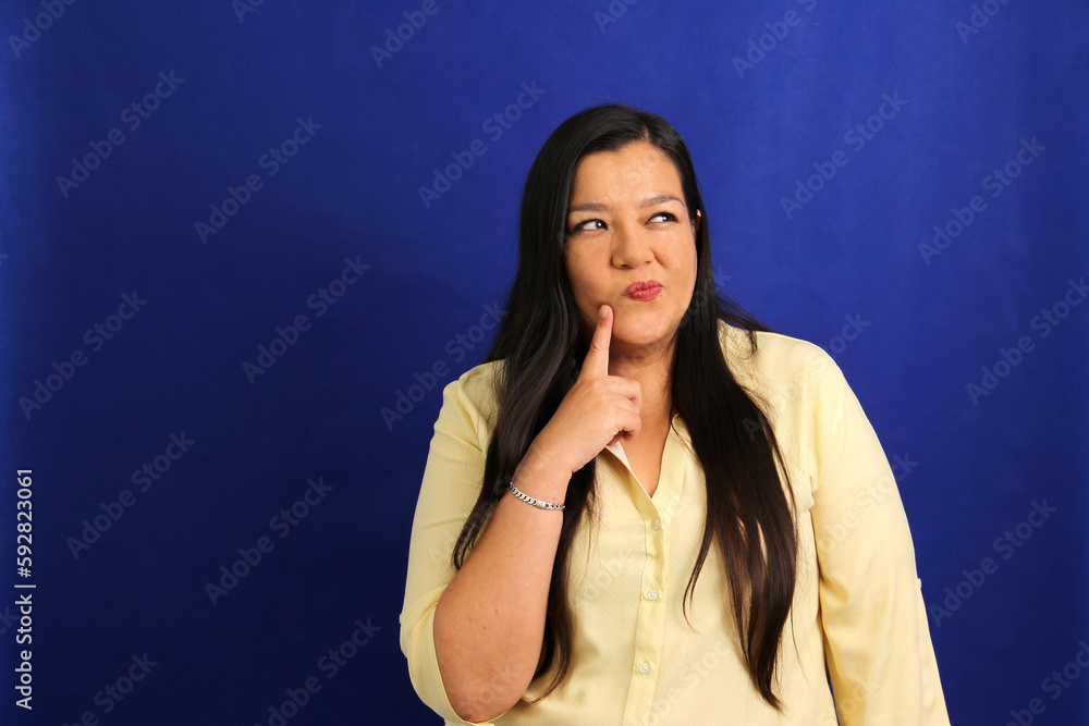 Adult Latino woman in his forties appears pensive and thoughtful Adult Latino woman in his forties appears pensive and thoughtful