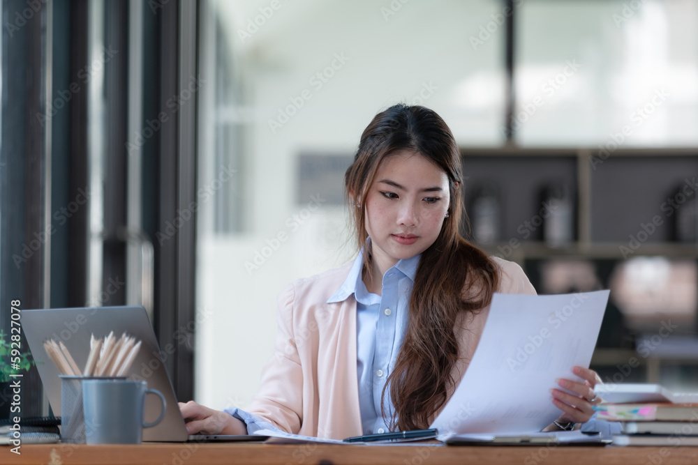Portrait of a Beautiful businesswoman sitting at a desk and working with a laptop computer. Portrait of a Beautiful businesswoman sitting at a desk and working with a laptop computer.