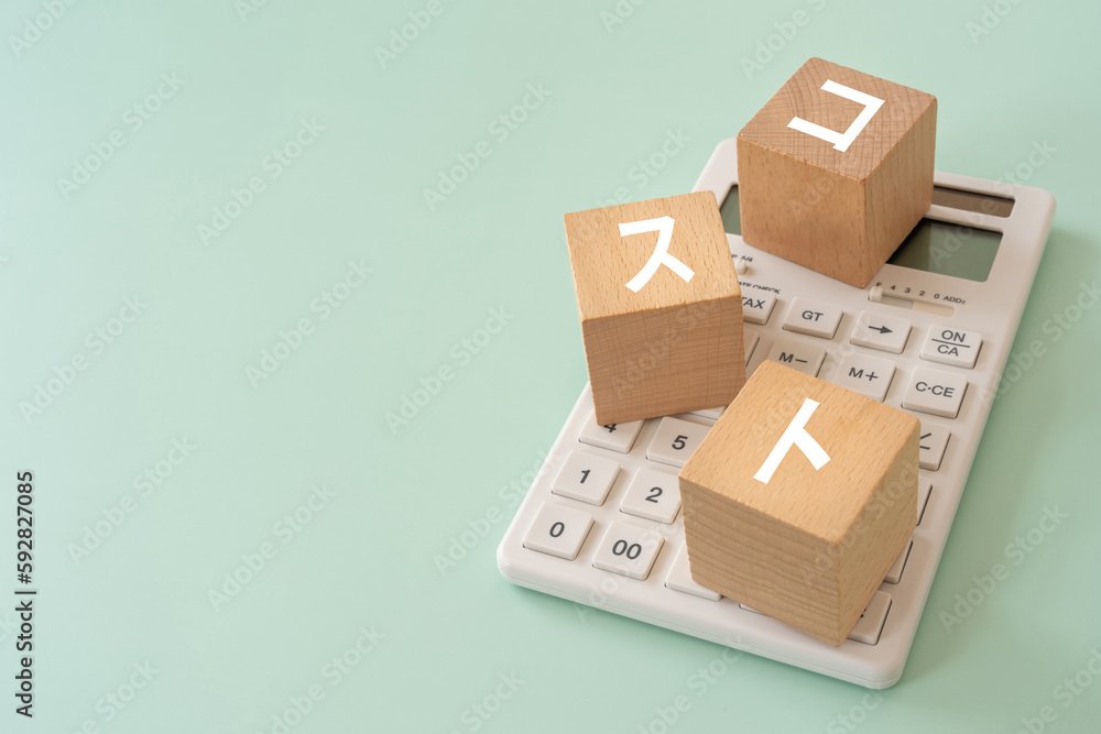 Obraz premium コストと書かれたブロックと電卓
