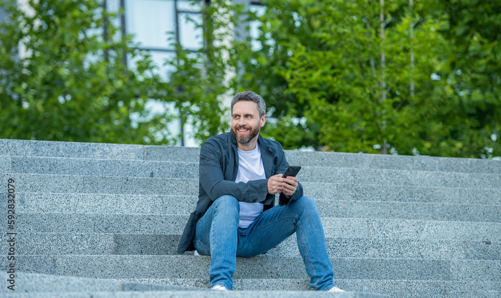 happy man messaging on phone outside. photo of man messaging on phone in hands. happy man messaging on phone outside. photo of man messaging on phone in hands.