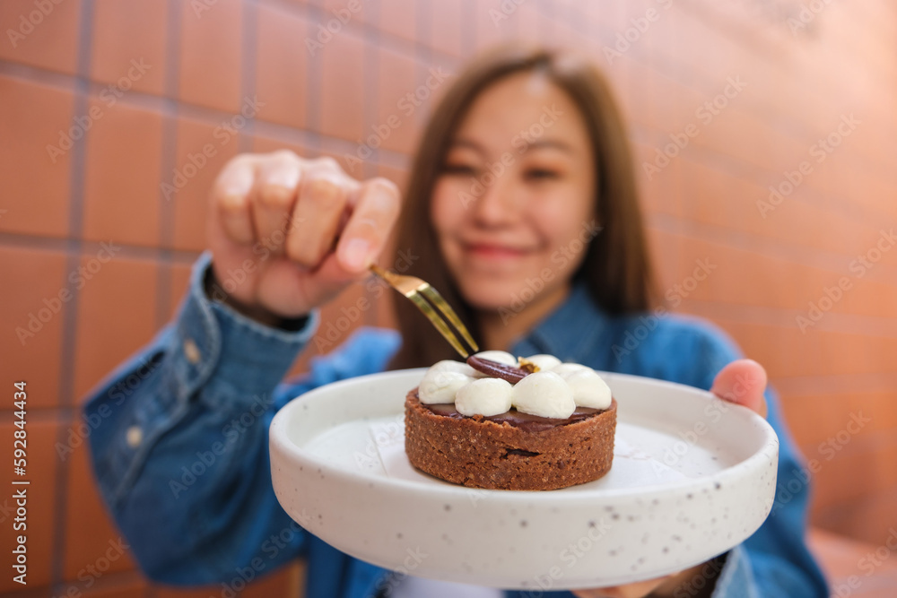Blurred image of a young woman holding a plate of a chocolate tart