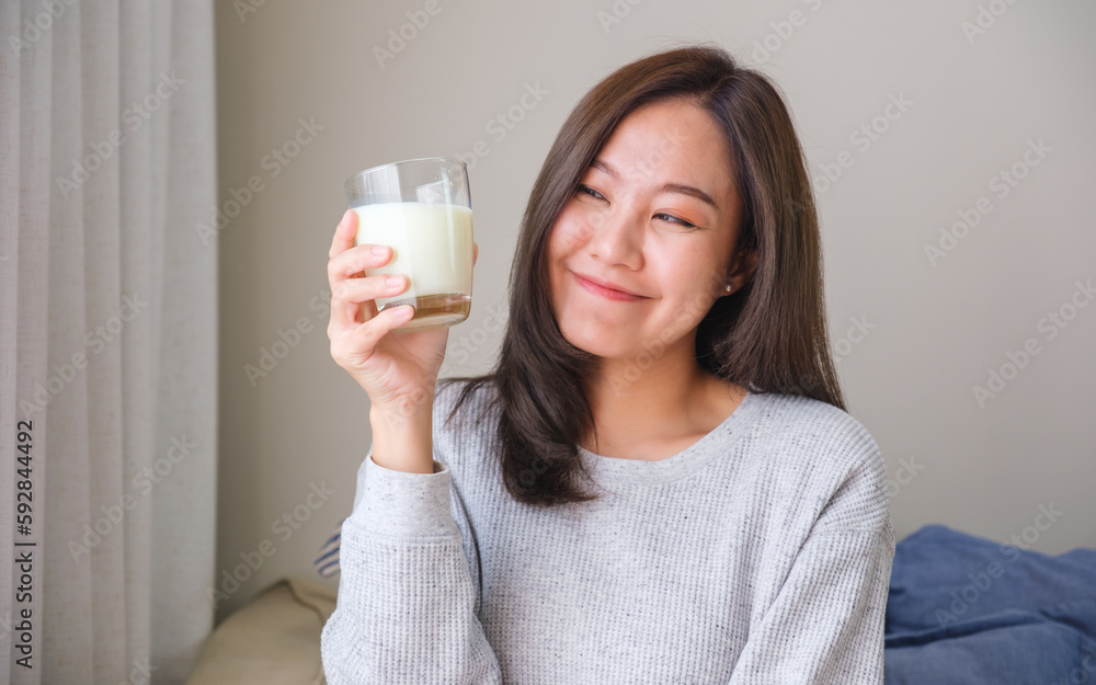 Portrait image of a young woman holding and showing a glass of fresh milk Portrait image of a young woman holding and showing a glass of fresh milk