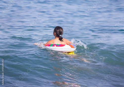 A beautiful teenage girl with an inflatable circle rides the waves