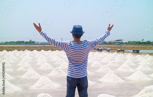 Man with arms outstretched to the sprawling salt pan in the harvest season, Samut Sakhon province of Thailand photo