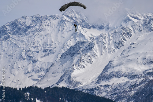 Army paraglider in the swiss Alps - snow covered mountains, lonely paraglider