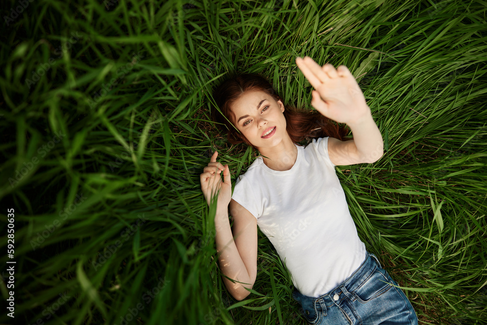 attractive teenager lying down on green grass with hands rised up to the air attractive teenager lying down on green grass with hands rised up to the air