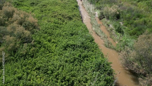 Aerial view of a small bridge over a creek surrounded by green fields